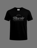 Premium black BLACOIR The Glint Script Tee featuring a metallic glitter-effect silver script logo, crew neckline, relaxed fit, and luxury minimalist design on a neutral grey background.