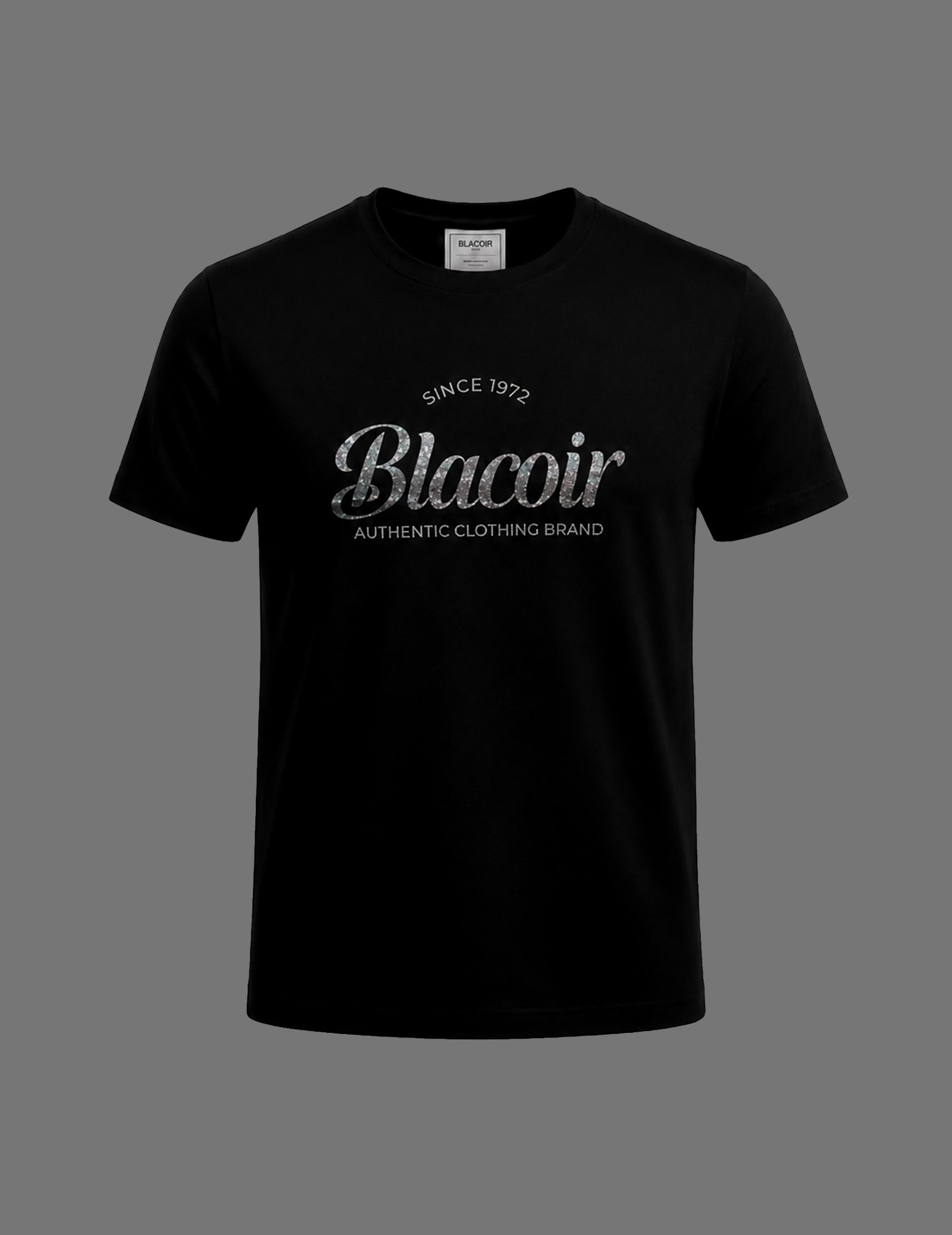 Premium black BLACOIR The Glint Script Tee featuring a metallic glitter-effect silver script logo, crew neckline, relaxed fit, and luxury minimalist design on a neutral grey background.