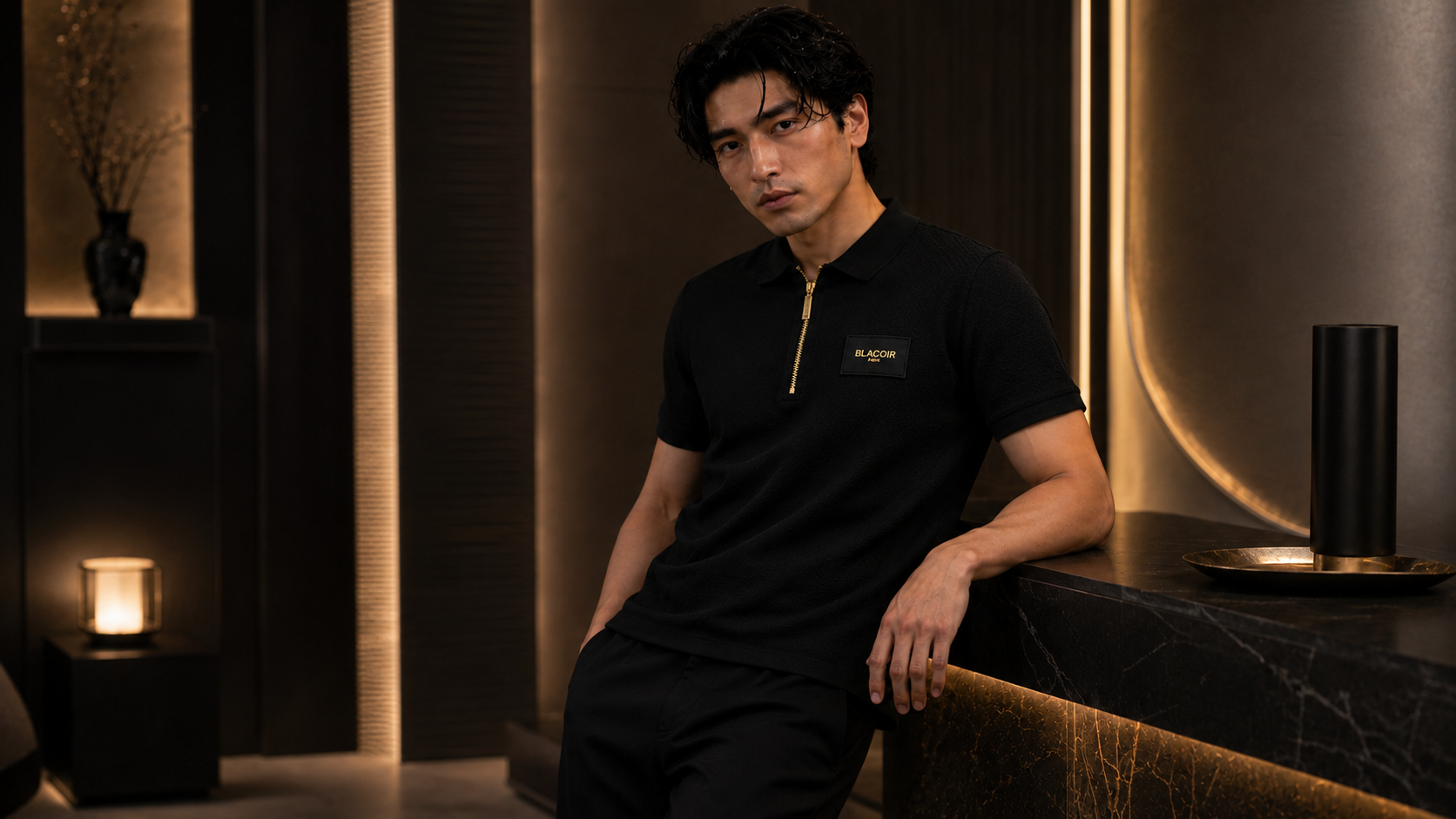 Blacoir men’s black zip polo from The Core Edit styled in a luxury modern interior with gold zipper and premium chest patch detail